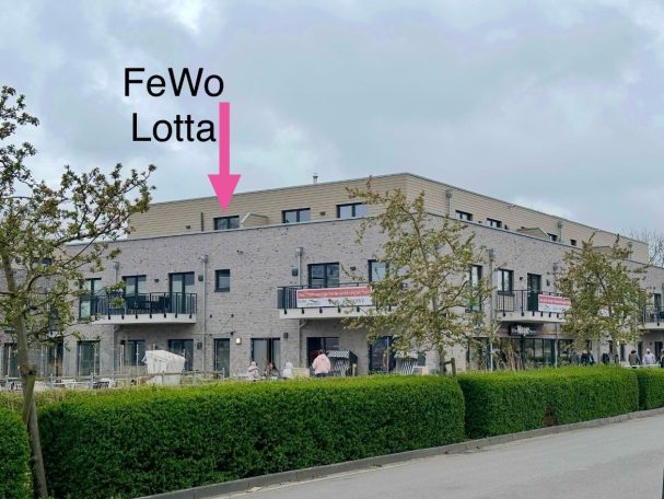 Küste 33 Fewo Lotta Moderne Wohnanlage mit der Beschriftung "FeWo Lotta" und grüner Bepflanzung.